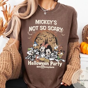 May include: Brown t-shirt with the text "Mickey's Not So Scary Halloween Party" and a graphic of Disney characters in skeleton costumes. The design includes Mickey Mouse, Minnie Mouse, Donald Duck, Daisy Duck, and Goofy. The shirt is from Walt Disney World.