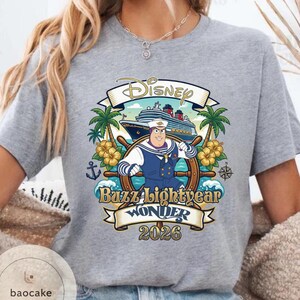 May include: Gray t-shirt featuring a Disney cruise design with Buzz Lightyear as a ship captain. The design includes a cruise ship, palm trees, and the text "Buzz Lightyear Wonder 2026".