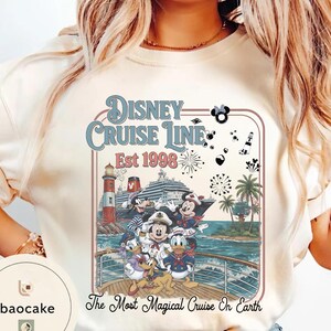 Puede incluir: Camiseta color crema con un gr&aacute;fico de Disney Cruise Line. El dise&ntilde;o incluye a Mickey Mouse, Minnie Mouse, Donald Duck y otros personajes en un crucero. El texto dice "Disney Cruise Line Est 1998" y "The Most Magical Cruise On Earth."