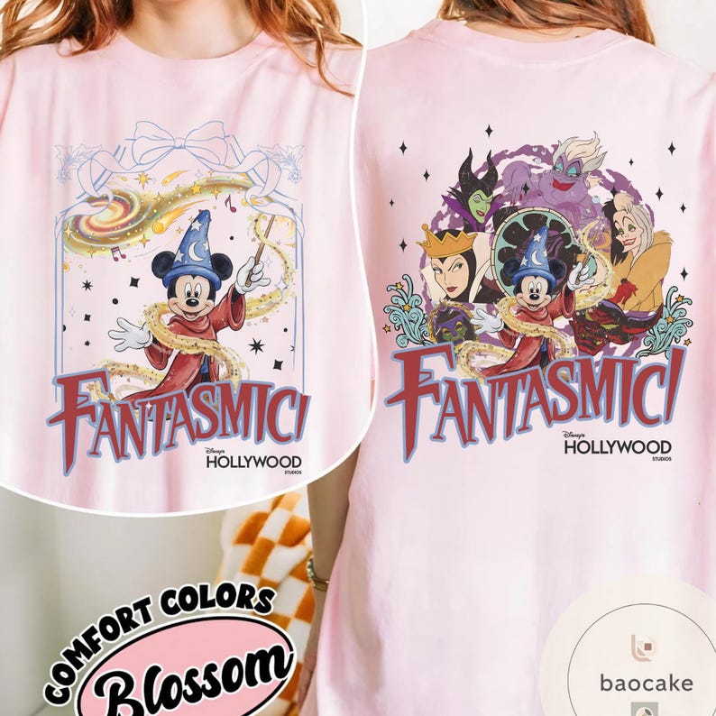 May include: Light pink t-shirt featuring a graphic of Mickey Mouse in a sorcerer's outfit with the text "Fantasmic!" and "Hollywood" on the front. The back of the shirt has a similar design with Disney villains. The shirt is from Comfort Colors.