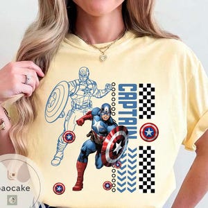 May include: Yellow t-shirt featuring Captain America. The design includes a full-color illustration of Captain America with his shield, a blue outline of the character, and the word "CAPTAIN" in blue and white checkered patterns.