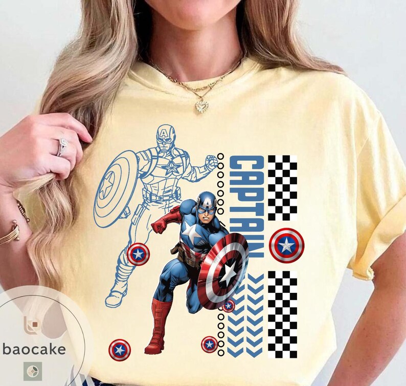 May include: Yellow t-shirt featuring Captain America. The design includes a full-color illustration of Captain America with his shield, a blue outline of the character, and the word "CAPTAIN" in blue and white checkered patterns.