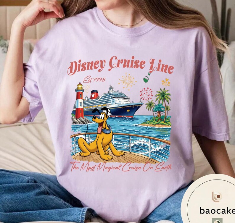 K&ouml;nnte beinhalten: Helllila T-Shirt mit einem Aufdruck von Pluto auf einem Kreuzfahrtschiff, einem Leuchtturm und Palmen. Der Text "Disney Cruise Line Est. 1998" und "The Most Magical Cruise On Earth" sind ebenfalls abgebildet.