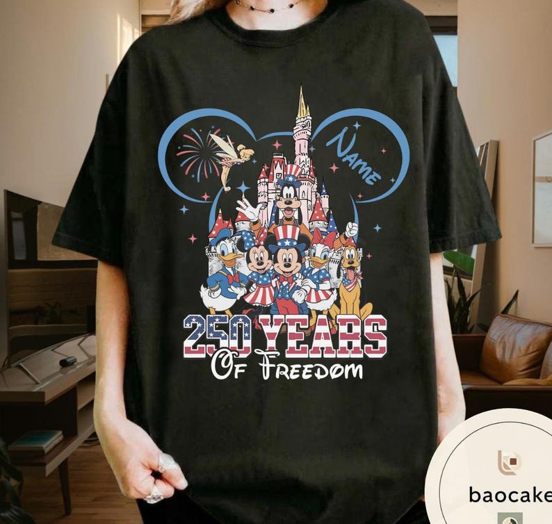 Peut inclure: T-shirt noir avec un motif patriotique Disney. Le motif comprend un ch&acirc;teau, des feux d'artifice et le texte "250 YEARS Of Freedom". Mickey Mouse, Donald Duck et d'autres personnages sont v&ecirc;tus de rouge, de blanc et de bleu.