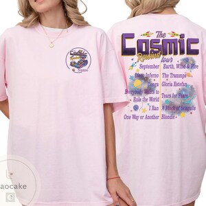 May include: A light pink t-shirt with the text "Cosmic Rewind Tour" on the back, listing bands like Earth, Wind & Fire and Blondie. The front features a circular graphic with the word "Cosmic" and the word "Name".