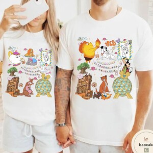 May include: White t-shirts with colorful cartoon character graphics. One shirt features a kangaroo, teapot, and other characters. The other shirt has a lion, dalmatian dogs, and other characters. The text on the shirts reads "Happiest Day on Earth."