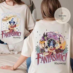 May include: Cream-colored t-shirt featuring a colorful graphic of Mickey Mouse in a sorcerer's hat, with the text "Fantasmici Hollywood" in red and blue. The back of the shirt shows various Disney villains and Mickey Mouse.