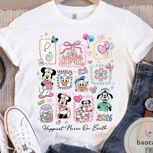 May include: White t-shirt featuring a colorful design with Disney characters in nurse attire. The design includes Mickey and Minnie Mouse, Donald and Daisy Duck, and Goofy. The text "Happiest Nurse On Earth" is printed at the bottom, with the year "2026".