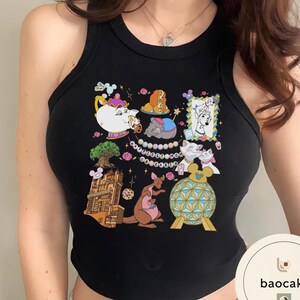 May include: Black tank top featuring a colorful cartoon collage. The design includes images of animated characters, a teapot, a tree, a kangaroo, and a decorative ball. The tank top is sleeveless and has a round neckline.