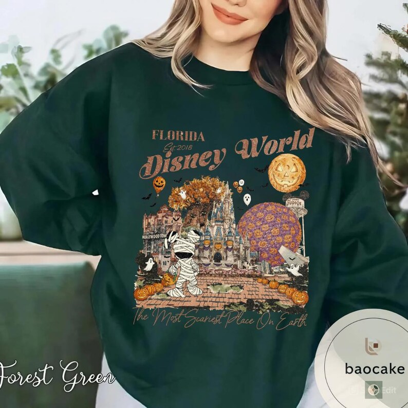 Op de afbeelding: Bospaarse sweatshirt met een Disney World Halloween-afbeelding. Het ontwerp bevat een mummie, pompoenen, een kasteel en de tekst "Florida Disney World" en "The Most Scariest Place On Earth."