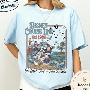 Puede incluir: Camiseta azul claro con un dise&ntilde;o de Disney Cruise Line. El dise&ntilde;o incluye a Mickey Mouse, Minnie Mouse, Donald Duck y otros personajes en un crucero, con el texto "Disney Cruise Line Est 1998" y "The Most Magical Cruise On Earth."
