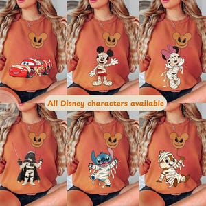 May include: A collection of orange t-shirts featuring various Disney characters in Halloween-themed designs. Each shirt showcases a different character, including Lightning McQueen, Mickey Mouse, Minnie Mouse, Darth Vader, Stitch, and Chip, all wrapped as mummies. A Mickey Mouse jack-o'-lantern balloon is also featured.