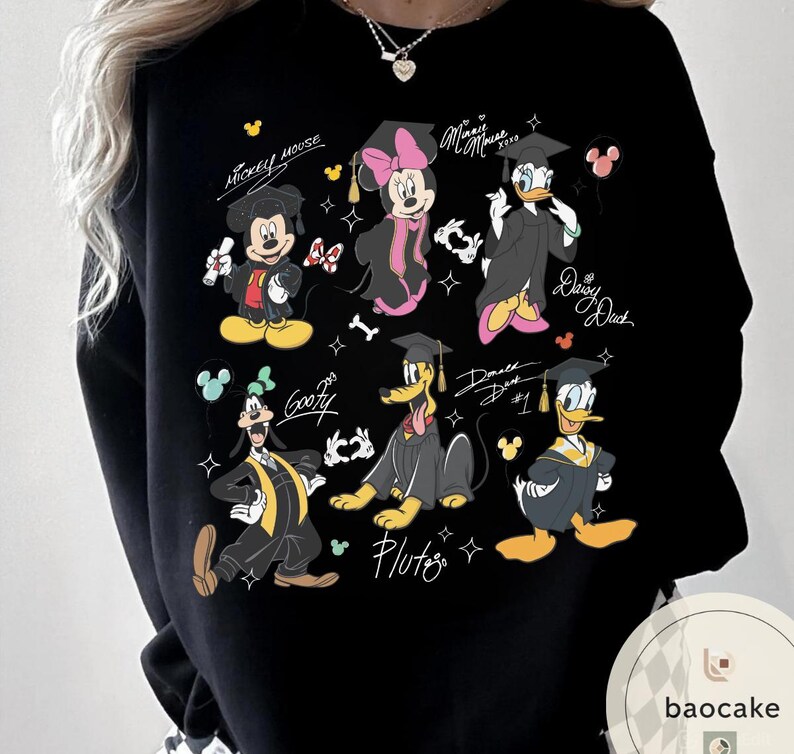 May include: Black sweatshirt featuring cartoon characters Mickey Mouse, Minnie Mouse, Daisy Duck, Donald Duck, Goofy, and Pluto in graduation attire. Each character is wearing a graduation cap and gown. The names of the characters are written above or below them.