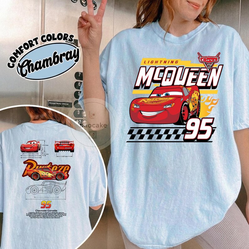 May include: A light blue t-shirt featuring a graphic of the red race car Lightning McQueen with the text "McQueen" and "95" on the front. The back of the shirt displays technical diagrams of the car, the Rust-eze logo, and the text "Chevrolet Corvette".
