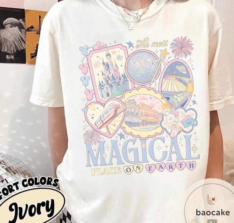 May include: Cream-coloured t-shirt with a pastel graphic design featuring a castle, Spaceship Earth, and other theme park icons. The text "MAGICAL PLACE ON EARTH" is displayed in blue and pink.