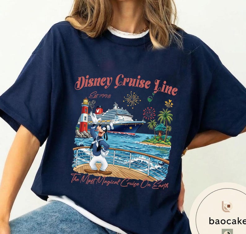 K&ouml;nnte beinhalten: Marineblaues T-Shirt mit einem Disney Cruise Line-Motiv. Das Design zeigt ein Kreuzfahrtschiff, einen Leuchtturm, Palmen, Feuerwerk und Goofy. Der Text auf dem Shirt lautet "Disney Cruise Line Est. 1998" und "The Most Magical Cruise On Earth."