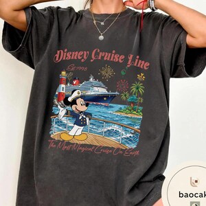 K&ouml;nnte beinhalten: Dunkelgraues T-Shirt mit einer farbenfrohen Grafik von Mickey Mouse auf einem Kreuzfahrtschiff. Das Design enth&auml;lt den Text "Disney Cruise Line" und "The Most Magical Cruise On Earth". Das T-Shirt hat einen Vintage-Look.