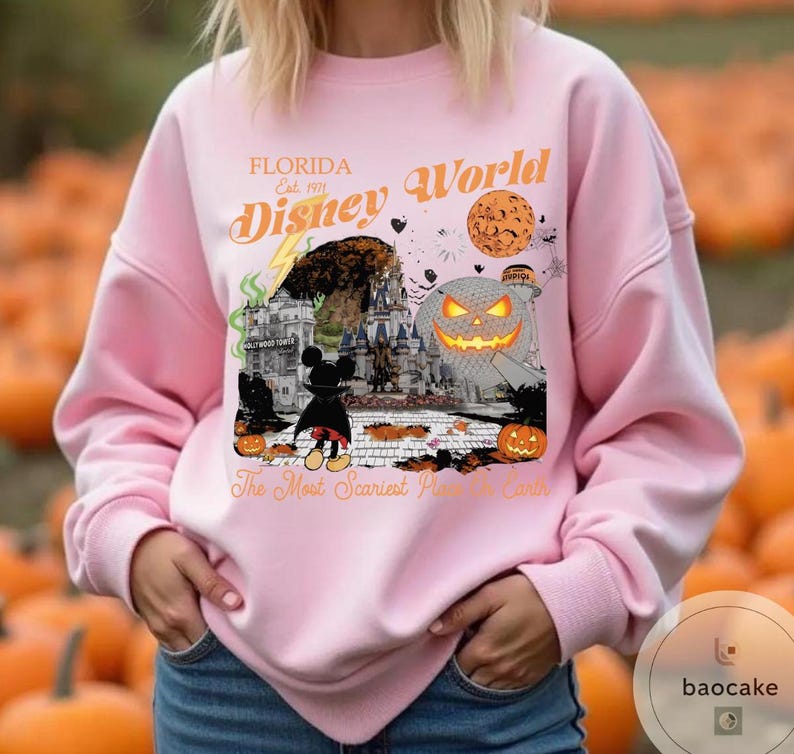 May include: Pink sweatshirt with a graphic featuring "Florida Disney World" text and Halloween-themed imagery. The design includes a castle, Mickey Mouse, pumpkins, and the phrase "The Most Scariest Place on Earth."