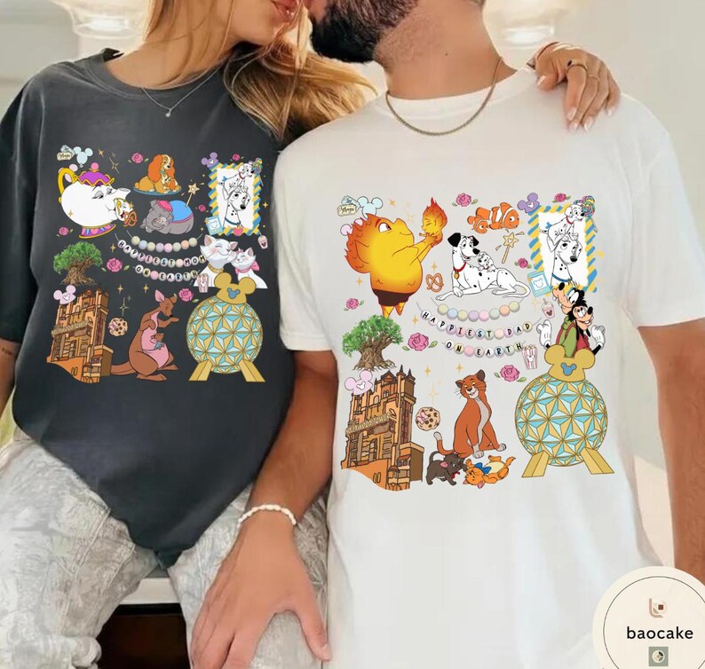 May include: Two t-shirts, one dark gray and one white, each featuring colorful cartoon character designs. The designs include various characters, flowers, and architectural elements. The white shirt has the text "Happiest Day on Earth".