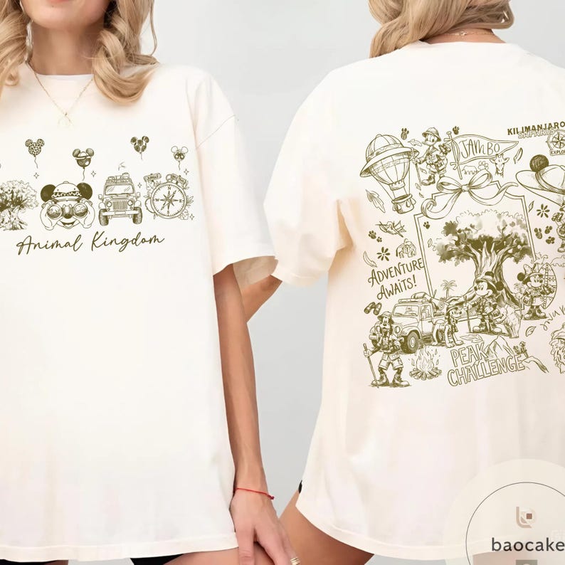 May include: Cream-colored t-shirt with a green graphic design. The front features "Animal Kingdom" text and themed illustrations. The back displays a detailed map with the text "Adventure Awaits!" and "Peak Challenge."