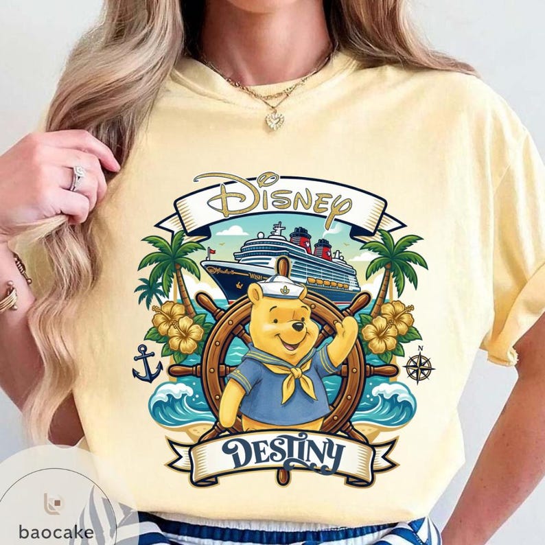 May include: Yellow t-shirt featuring a Disney cruise design. The graphic includes Winnie the Pooh in a sailor outfit at a ship's wheel, with a cruise ship in the background. The word "Disney" is above, and "Destiny" below.