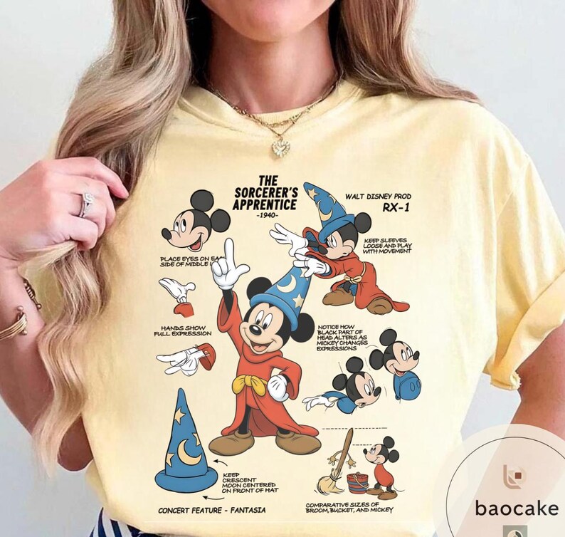 May include: A light yellow t-shirt featuring a graphic of Mickey Mouse as the Sorcerer's Apprentice from Fantasia. The design includes illustrations and text detailing the character's features and the film's production. The text reads "The Sorcerer's Apprentice - 1940".