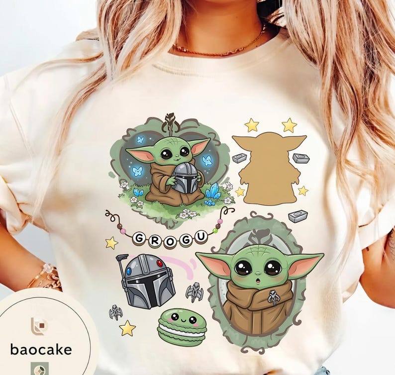 May include: A cream-colored t-shirt featuring a graphic print of Grogu, a Mandalorian helmet, a green macaron, and stars. The design includes the text "GROGU" on a string of beads, surrounded by decorative frames and small icons in shades of green, brown, and grey.