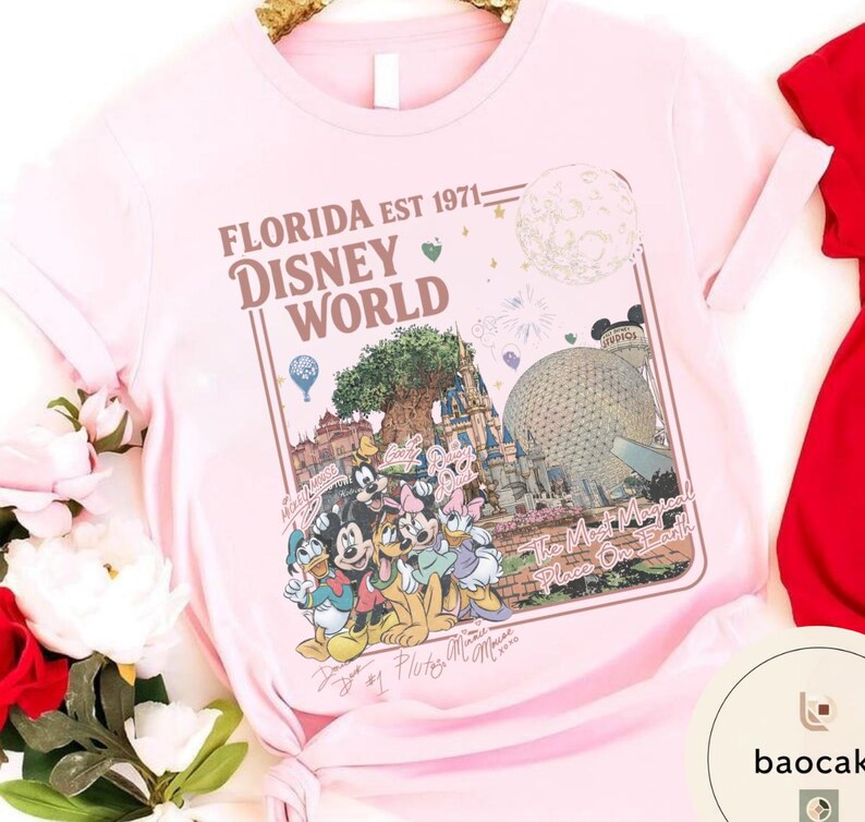 May include: A light pink short-sleeved t-shirt featuring a graphic print of Disney World landmarks and characters. The text reads Florida Est 1971 Disney World and The Most Magical Place On Earth, accompanied by illustrations of Mickey, Minnie, and friends.