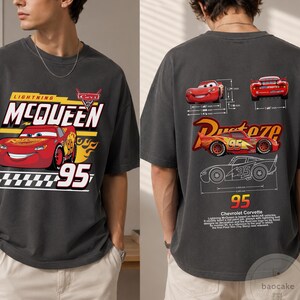 May include: A charcoal grey t-shirt featuring a front graphic of Lightning McQueen with the text "Lightning McQueen" and "95" above a checkered pattern. The back displays technical diagrams of the car, the text "Rust-eze," and "95."