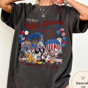 Puede incluir: Camiseta gris oscuro con un gr&aacute;fico colorido que celebra 250 a&ntilde;os. El dise&ntilde;o incluye fuegos artificiales, globos y personajes de Disney. El texto incluye "Oh Boy!" y "Celebrating of Joy."