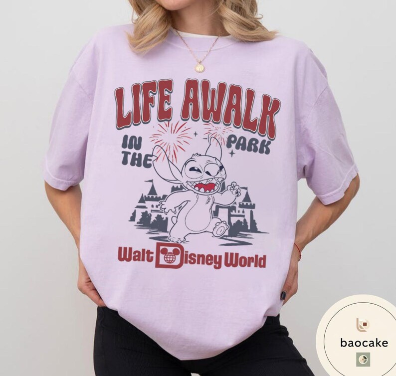 May include: A light purple t-shirt with the text "LIFE AWALK IN THE PARK" in red and white. The shirt features a cartoon image of Stitch from Disney's Lilo & Stitch, and the words "Walt Disney World".