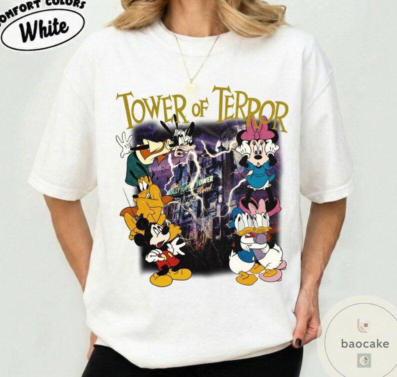 May include: White t-shirt featuring a graphic of Disney characters, including Mickey Mouse, Goofy, and Minnie Mouse, with the text "Tower of Terror." The design has a vintage, distressed look with a purple and yellow color scheme.