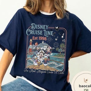 Puede incluir: Camiseta azul marino con un dise&ntilde;o de Disney Cruise Line. El dise&ntilde;o incluye a Mickey Mouse, Minnie Mouse, Donald Duck y Goofy en un crucero. El texto dice "Disney Cruise Line Est 1998" y "The Most Magical Cruise On Earth."