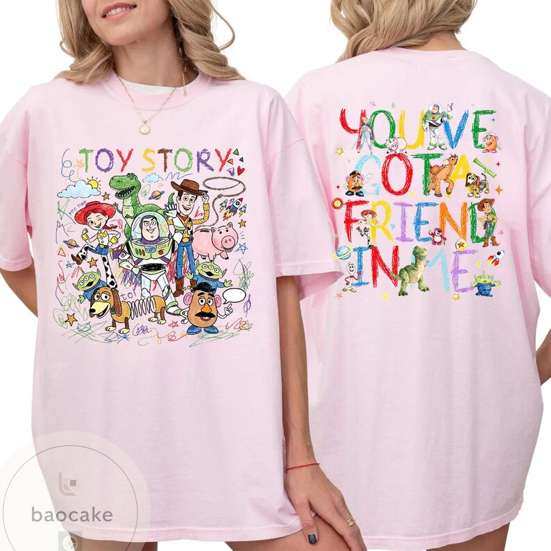 May include: Light pink t-shirt featuring colorful cartoon characters and the text "TOY STORY" on the front. The back of the shirt displays the phrase "YOU'VE GOT A FRIEND IN ME" with more cartoon characters.