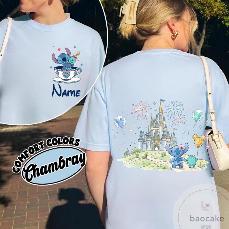 May include: Light blue t-shirt featuring Stitch in a teacup on the front and a castle scene on the back. The front has the word "Name" and the back has fireworks and balloons. The shirt is labeled "Comfort Colors Chambray".