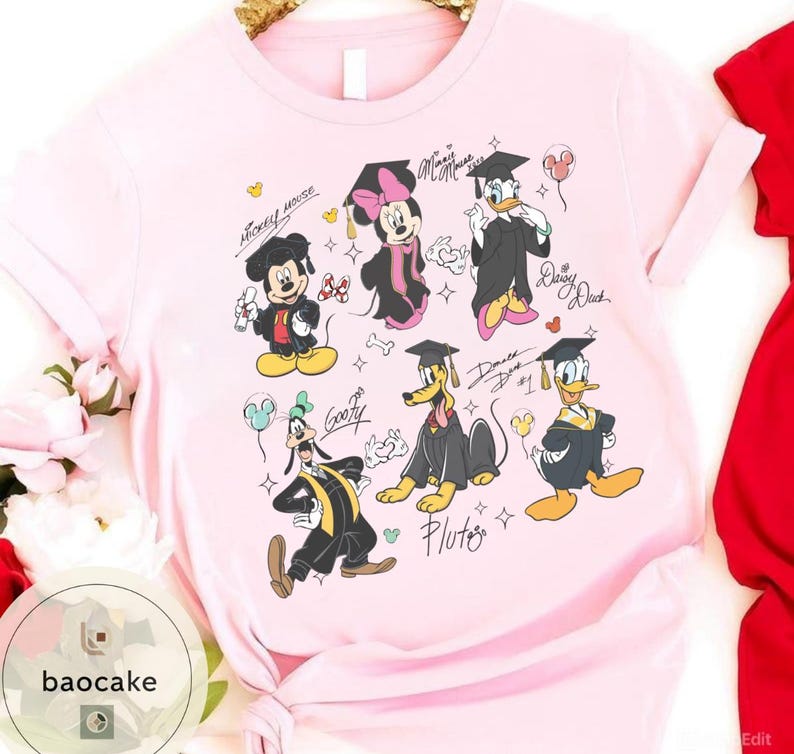 May include: Light pink t-shirt featuring cartoon characters Mickey Mouse, Minnie Mouse, Donald Duck, Daisy Duck, Goofy, and Pluto in graduation attire. Each character is wearing a graduation cap and gown. The shirt has character signatures.
