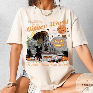 May include: Cream-colored t-shirt featuring a Halloween-themed Disney World graphic. The design includes a pumpkin, Mickey Mouse, and the text "Florida Disney World" and "The Most Scariest Place On Earth."