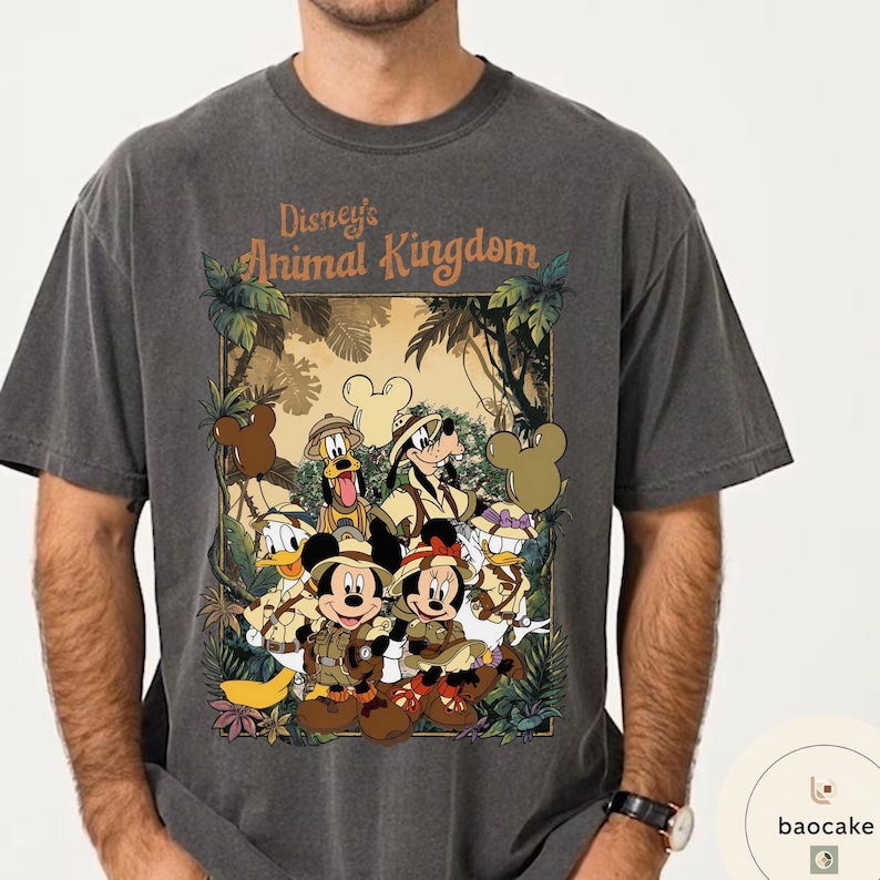 May include: Dark grey t-shirt featuring a graphic of Disney's Animal Kingdom characters, including Mickey and Minnie Mouse, Donald Duck, and Goofy, in safari attire. The shirt has the text "Disney's Animal Kingdom" in a jungle-themed design.