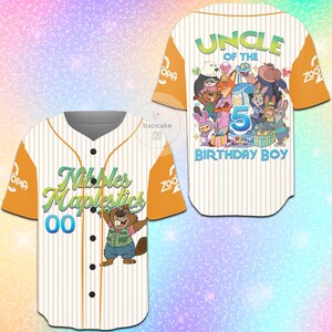 K&ouml;nnte beinhalten: Wei&szlig;-oranges Baseball-Trikot mit vertikalen Streifen. Auf der Vorderseite steht "Nibbles Maplestick" und ein Cartoon-Biber. Auf der R&uuml;ckseite steht "Uncle of the 5 Birthday Boy" mit Cartoon-Figuren. &Auml;rmel mit "Zootopia" und "OPIA" Logos.