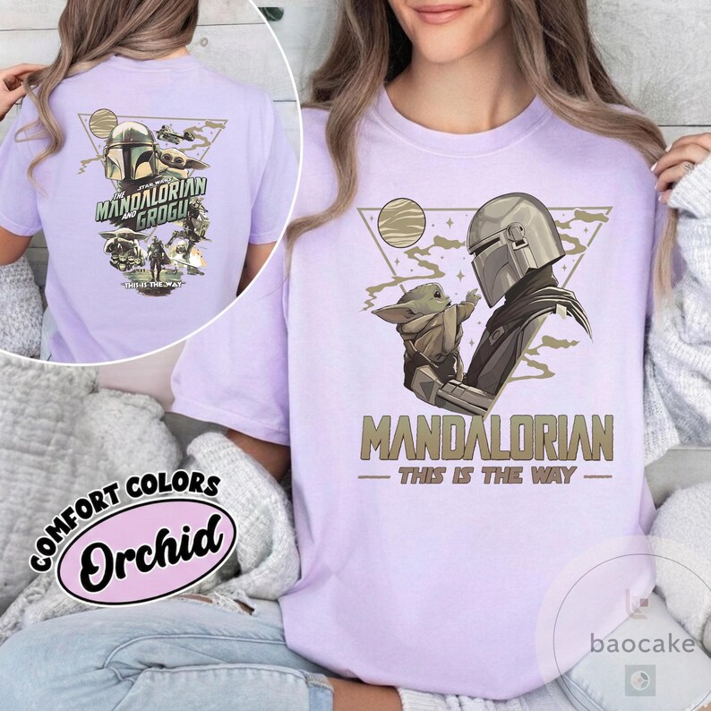 Op de afbeelding: Een lichtpaars T-shirt met een afbeelding van The Mandalorian en Grogu. Het ontwerp bevat de tekst "MANDALORIAN" en "THIS IS THE WAY". De achterkant van het shirt heeft ook een afbeelding met de tekst "MANDALORIAN GROGU".
