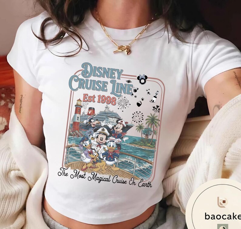 Puede incluir: Camiseta blanca con un gr&aacute;fico colorido de personajes de Disney en un crucero. El dise&ntilde;o incluye el texto "Disney Cruise Line Est 1998" y "The Most Magical Cruise On Earth."