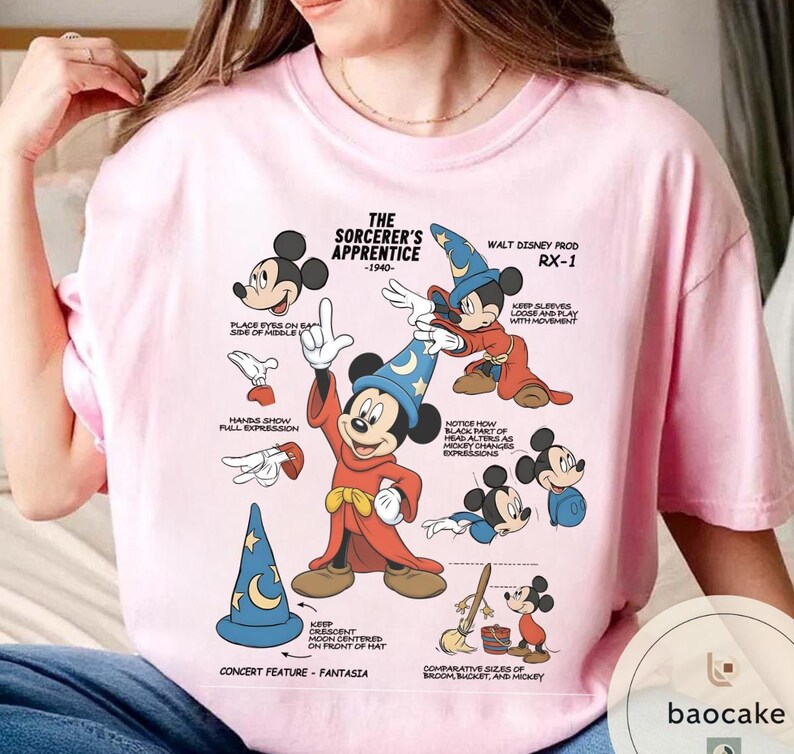 May include: Pink t-shirt featuring a graphic of Mickey Mouse as the Sorcerer's Apprentice, with text and illustrations from the 1940s. The design includes various poses and details, such as hand expressions and sleeve movement.