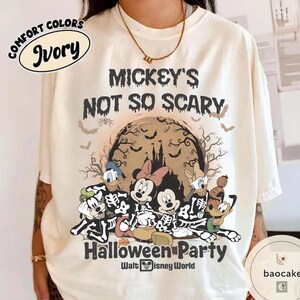 May include: Ivory-colored t-shirt with the text "Mickey's Not So Scary Halloween Party" and a graphic of Disney characters in skeleton costumes. The design includes bats, a castle, and the Walt Disney World logo.