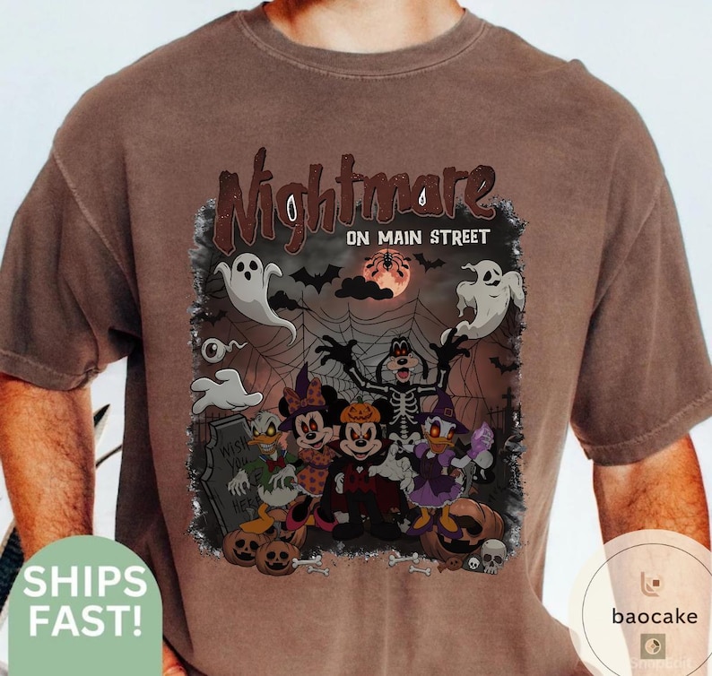 May include: Brown t-shirt with a Halloween-themed graphic. The graphic features cartoon characters dressed in costumes, ghosts, bats, and the text "Nightmare on Main Street".