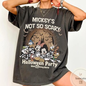 May include: Dark gray t-shirt featuring a Halloween design. The shirt displays the text "Mickey's Not So Scary Halloween Party" with Disney characters dressed as skeletons. The design includes a spooky castle, bats, and a full moon.