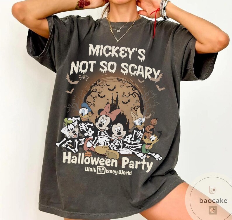 May include: Dark gray t-shirt featuring a Halloween design. The shirt displays the text "Mickey's Not So Scary Halloween Party" with Disney characters dressed as skeletons. The design includes a spooky castle, bats, and a full moon.