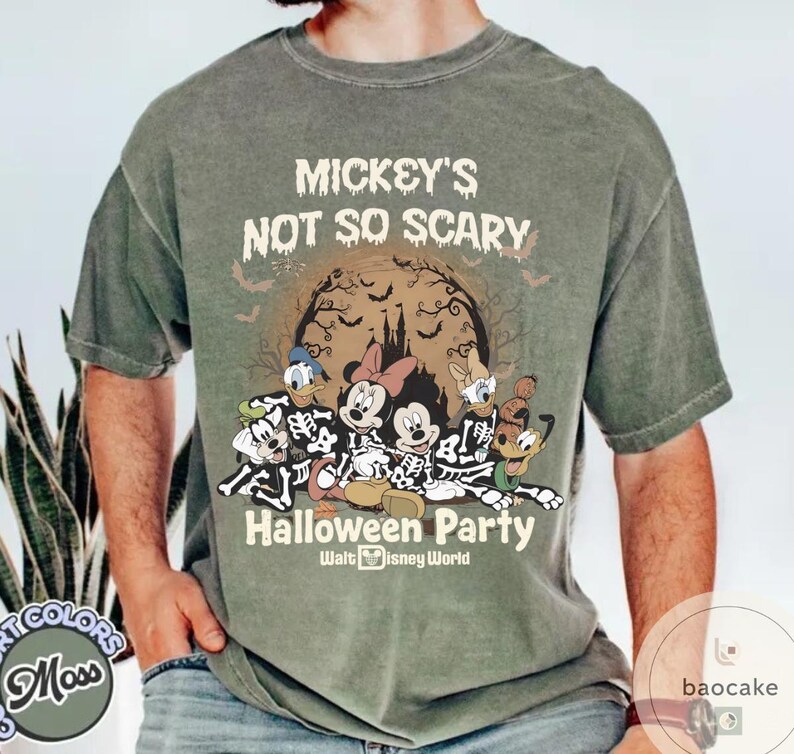 May include: Moss green t-shirt featuring a Halloween design with Mickey Mouse, Minnie Mouse, Donald Duck, Goofy, and Pluto dressed as skeletons. The shirt reads "Mickey's Not So Scary Halloween Party" with a spooky castle and bats.