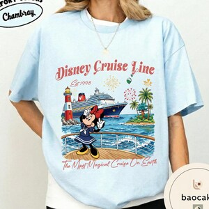K&ouml;nnte beinhalten: Hellblaues T-Shirt mit einem Disney Cruise Line-Motiv. Das Design zeigt Minnie Mouse auf einem Kreuzfahrtschiff, mit dem Text "Disney Cruise Line Est. 1998" und "The Most Magical Cruise On Earth". Das T-Shirt hat einen Rundhalsausschnitt und kurze &Auml;rmel.