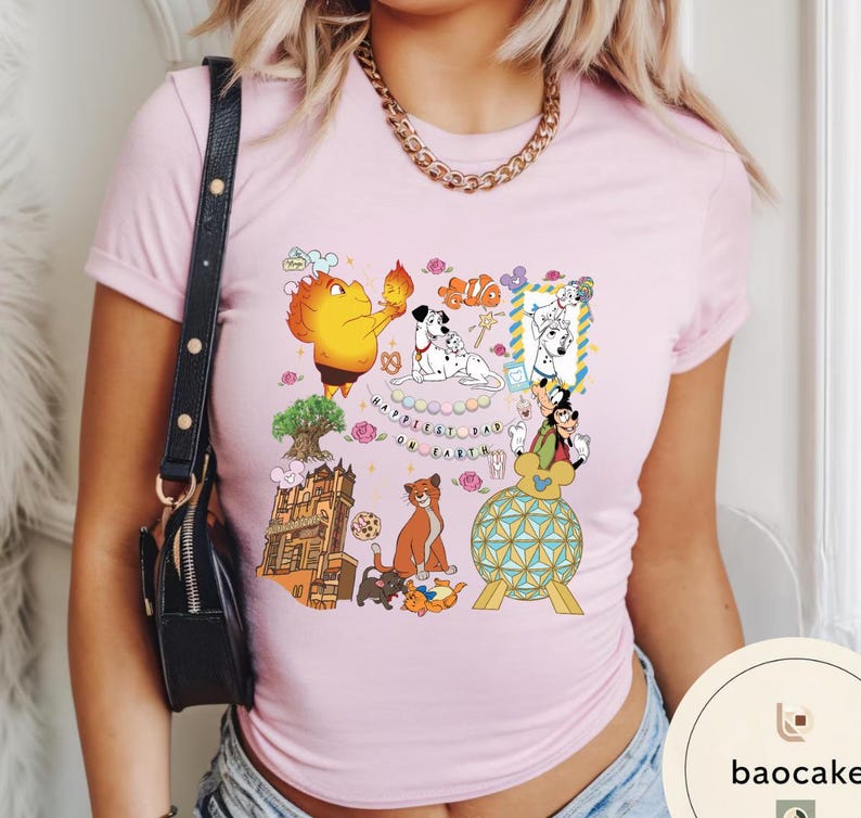 May include: Light pink t-shirt featuring colorful cartoon illustrations of various characters. The shirt includes the text "Happiest Dad on Earth" and other graphics. The shirt is made of a soft material.
