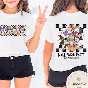 May include: White t-shirt featuring a Halloween-themed graphic with Disney characters. The front of the shirt displays a checkered pattern with cartoon characters. The back of the shirt has the words "Halloween Party" and more Disney characters.